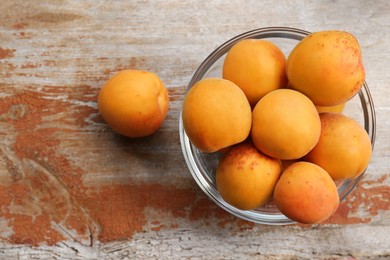 Photo of Glass bowl with delicious ripe apricots on wooden table, flat lay