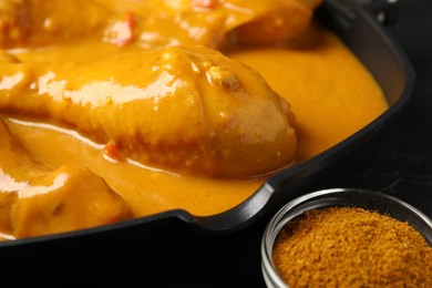 Photo of Tasty chicken curry and spice on black table, closeup