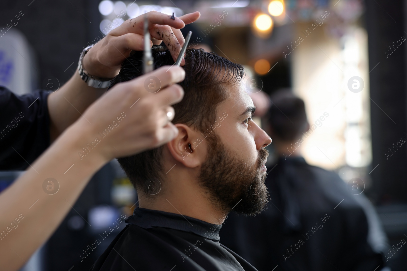 Photo of Professional hairdresser working with client in barbershop