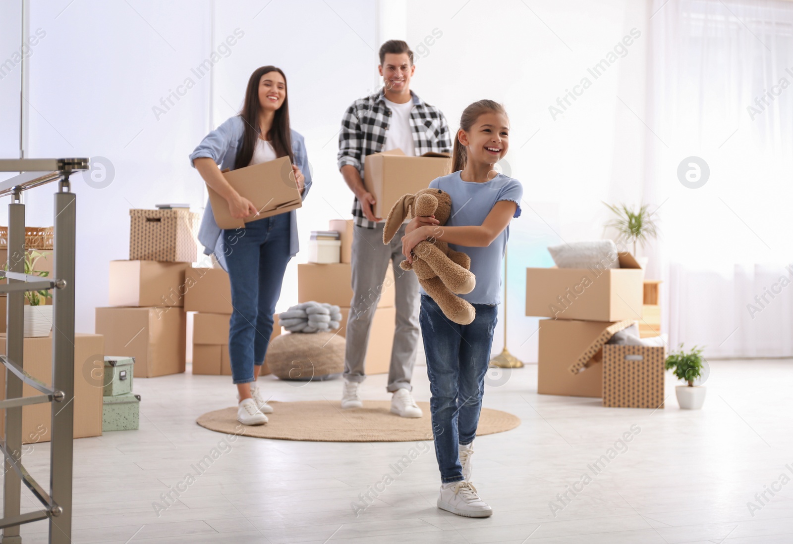 Photo of Happy family in room with cardboard boxes on moving day