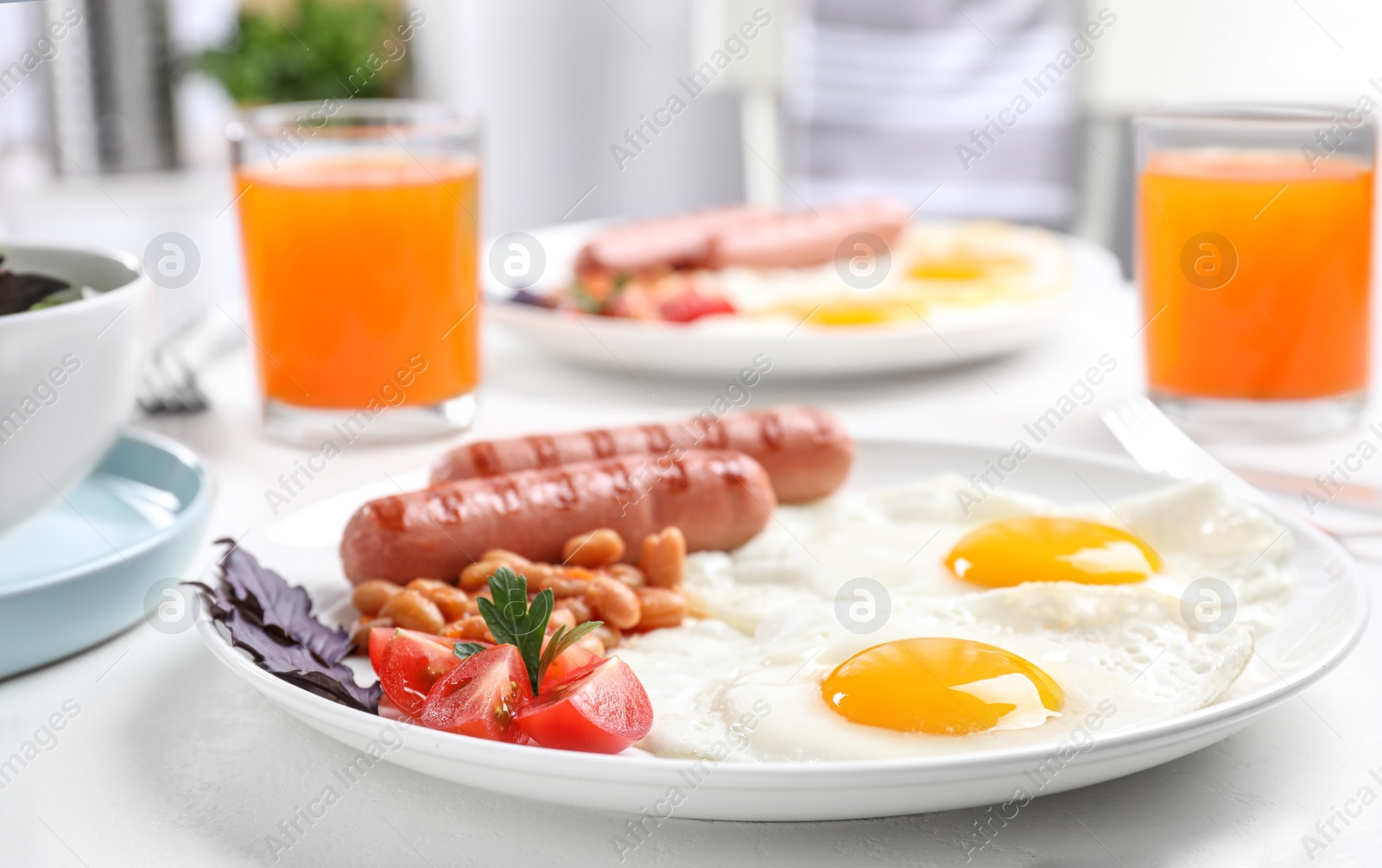 Photo of Delicious breakfast with fried eggs and sausages served on white table, closeup