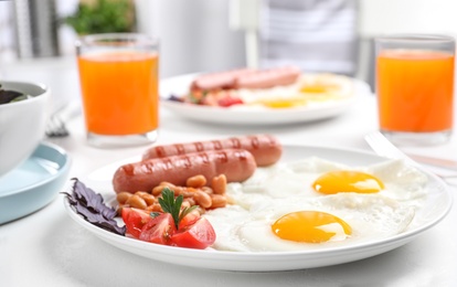 Photo of Delicious breakfast with fried eggs and sausages served on white table, closeup