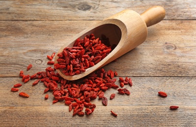 Photo of Scoop and dried goji berries on wooden table. Healthy superfood