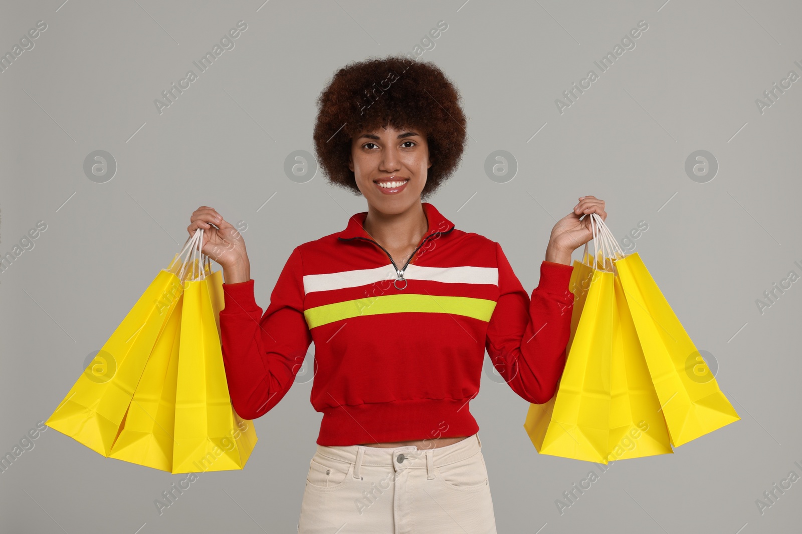 Photo of Happy young woman with shopping bags on grey background