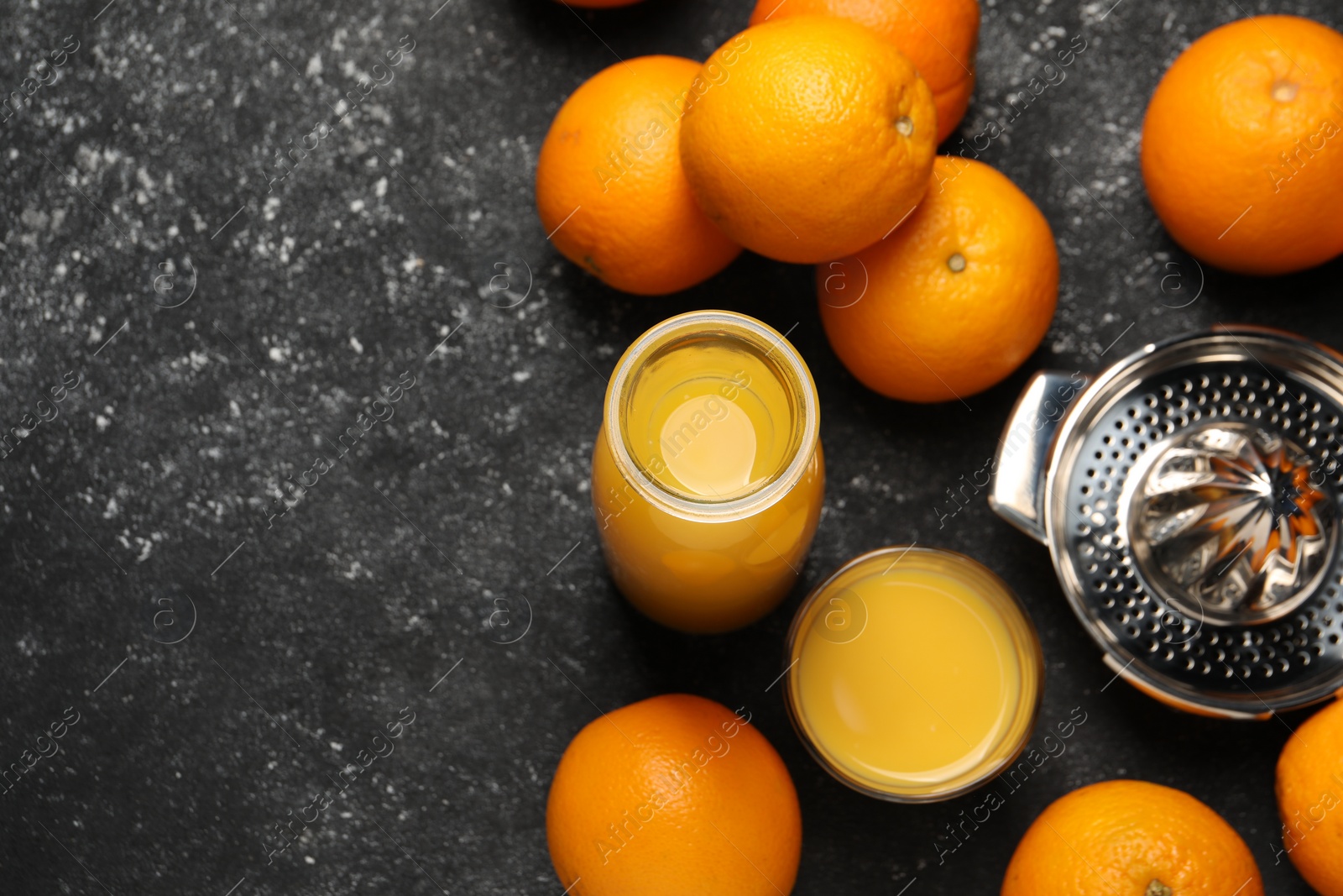 Photo of Tasty fresh oranges and juice on black table, flat lay. Space for text