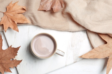 Flat lay composition with hot cozy drink and autumn leaves on wooden background