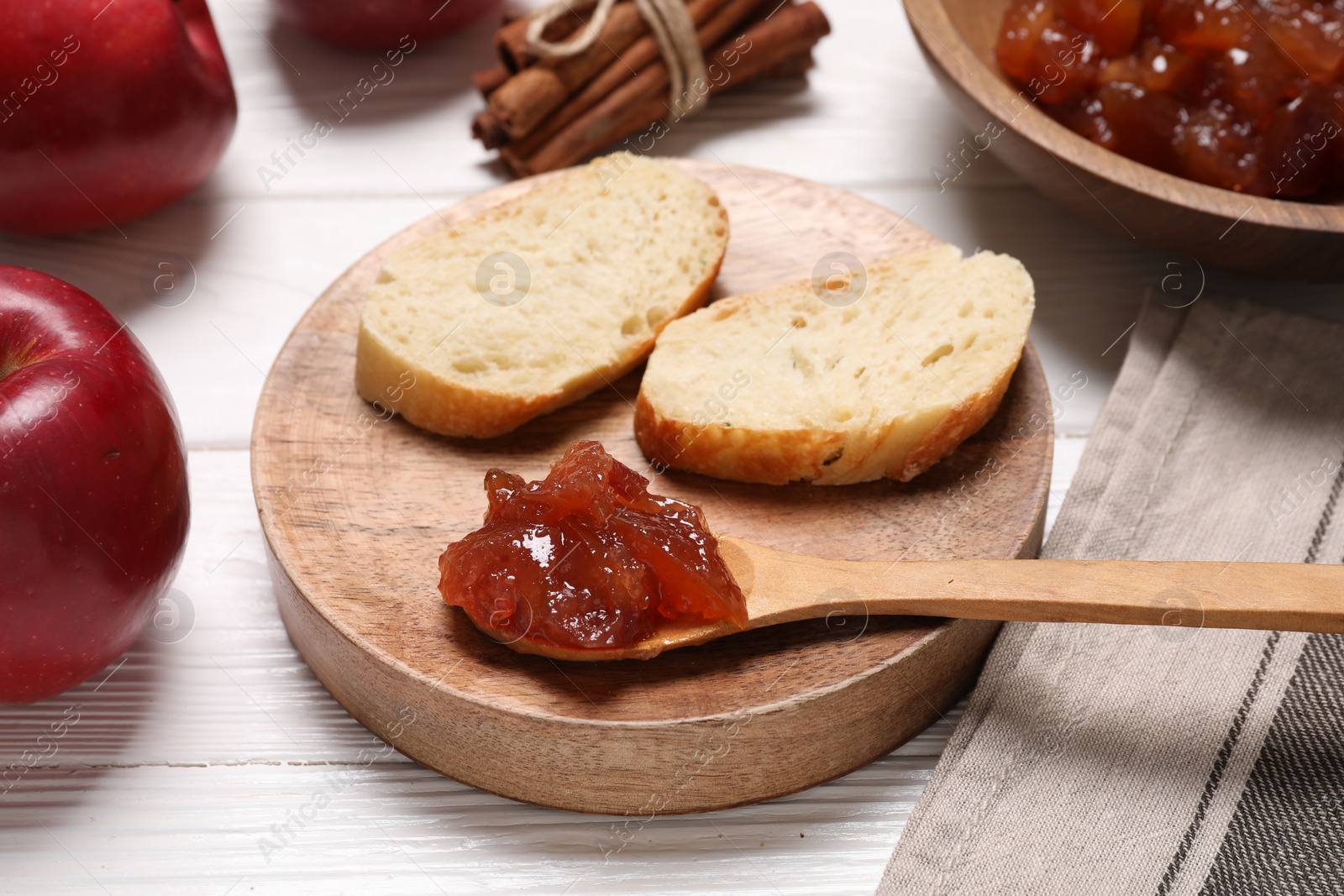 Photo of Delicious apple jam and bread slices on white wooden table