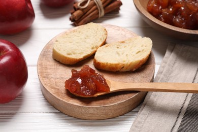 Photo of Delicious apple jam and bread slices on white wooden table