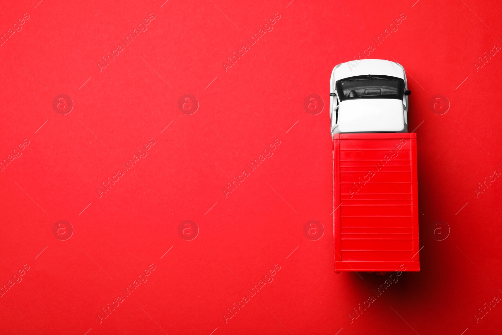 Photo of Top view of toy truck on red background, space for text. Logistics and wholesale concept