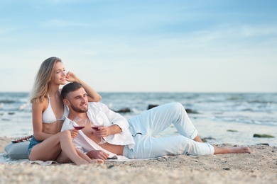 Photo of Young couple with glasses of wine on beach
