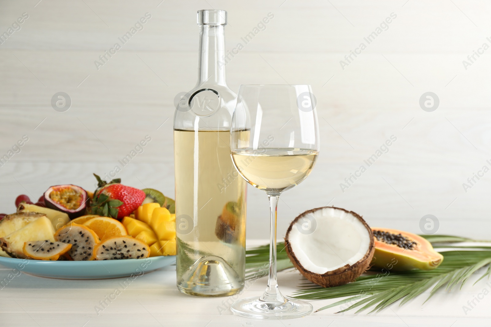 Photo of Delicious exotic fruits and wine on white wooden table