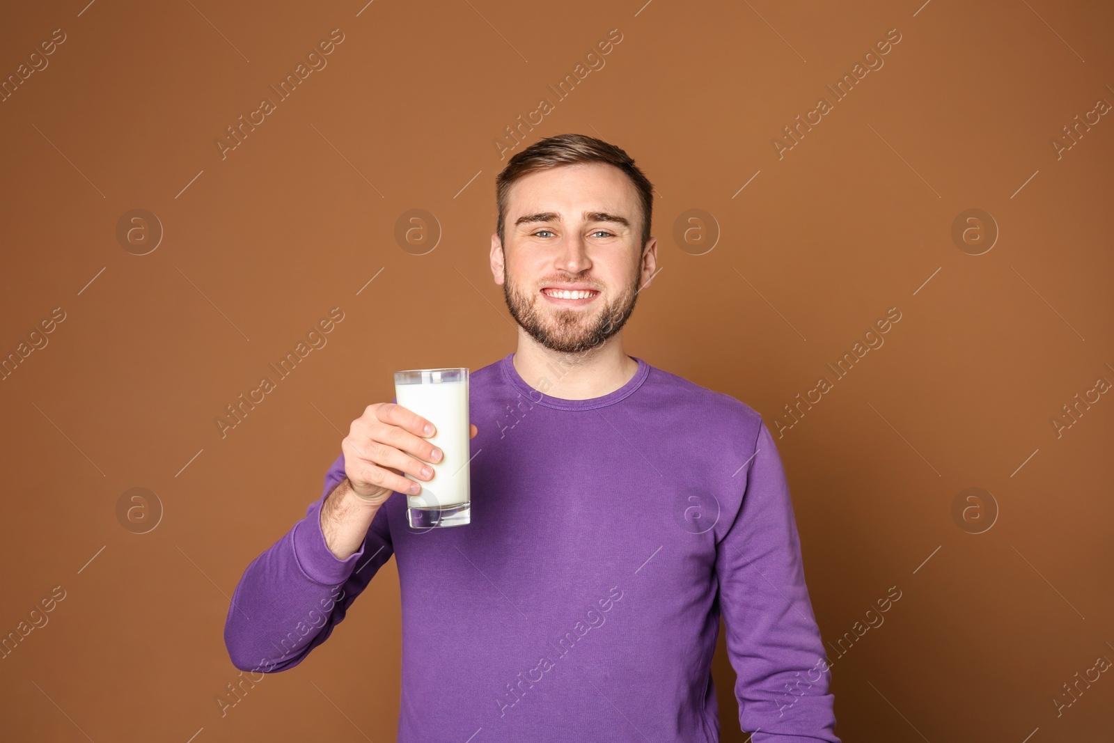 Photo of Young man with glass of tasty milk on color background