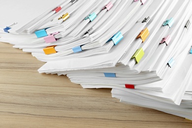 Photo of Stack of documents with binder clips on wooden table, closeup view