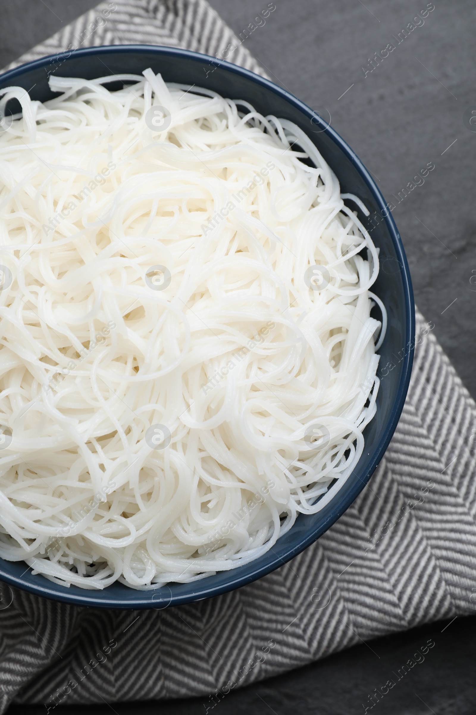 Photo of Bowl with cooked rice noodles on black table, top view