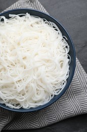 Bowl with cooked rice noodles on black table, top view
