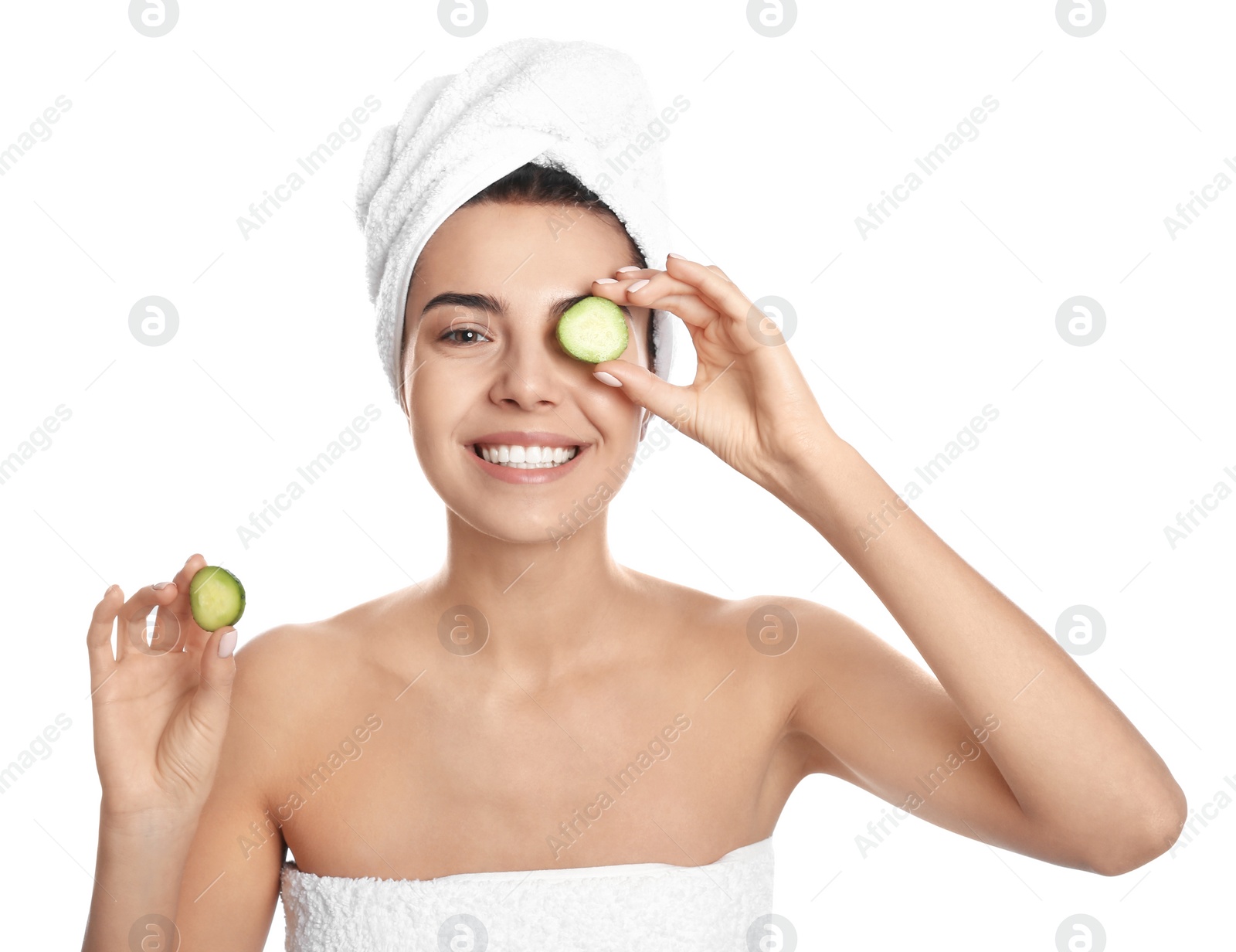 Photo of Happy young woman with towel holding cucumber slices on white background. Organic face mask