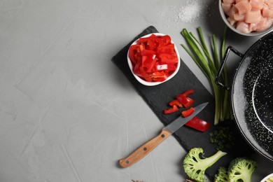 Wok pan, chicken and other products on light grey table, flat lay. Space for text