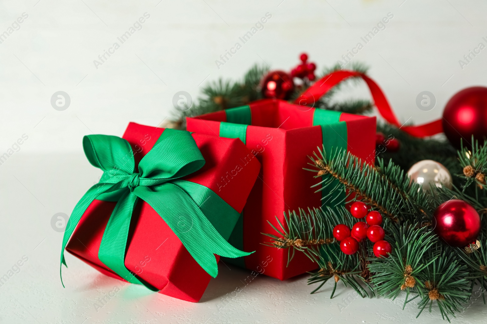 Photo of Red gift box with fir tree branches and Christmas balls on white table