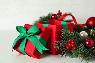 Red gift box with fir tree branches and Christmas balls on white table