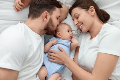 Happy family. Parents with their cute baby on bed, top view