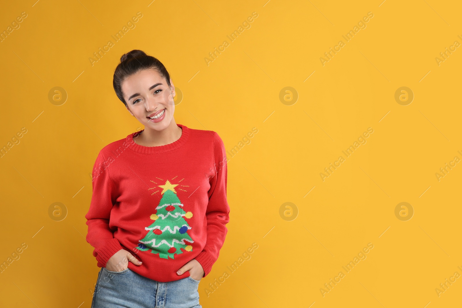 Photo of Young woman in Christmas sweater on yellow background, space for text