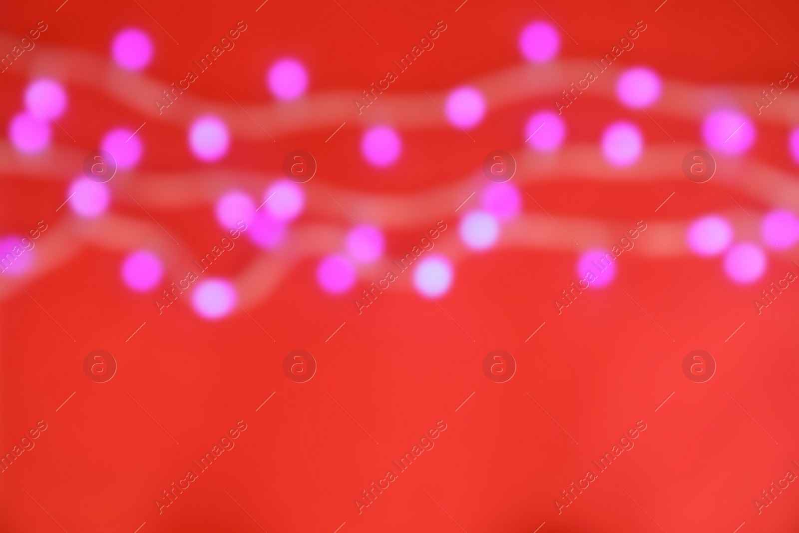 Photo of Blurred view of glowing Christmas lights on color background, top view