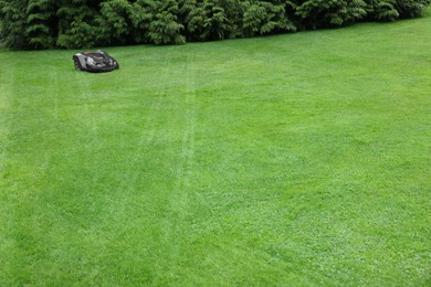 Photo of Modern lawn mower on green grass outdoors. Space for text