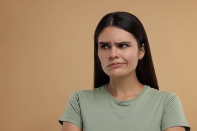 Portrait of resentful woman on beige background, space for text