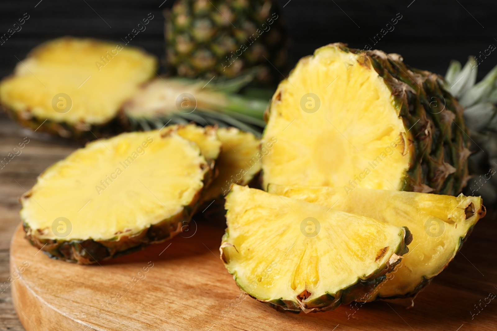 Photo of Cut fresh juicy pineapple on wooden board, closeup