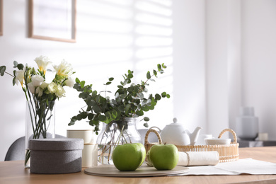 Photo of Apples and tea set on wooden table indoors. Stylish interior design