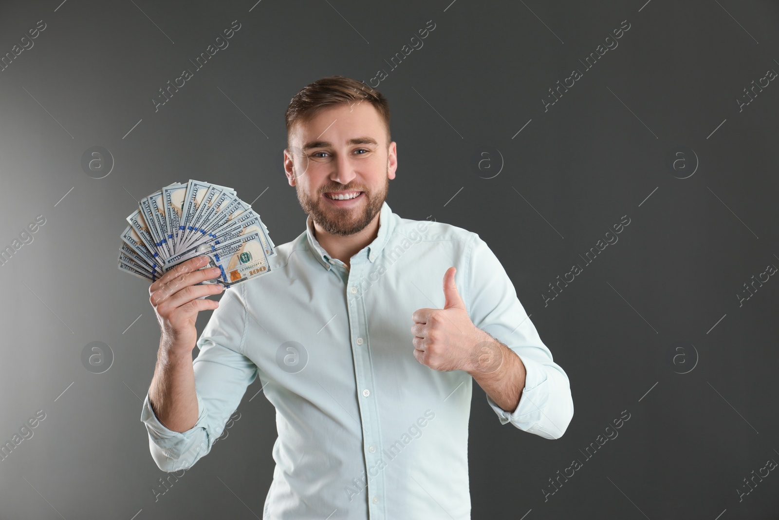 Photo of Portrait of happy young man with money on grey background