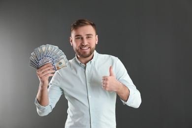 Portrait of happy young man with money on grey background