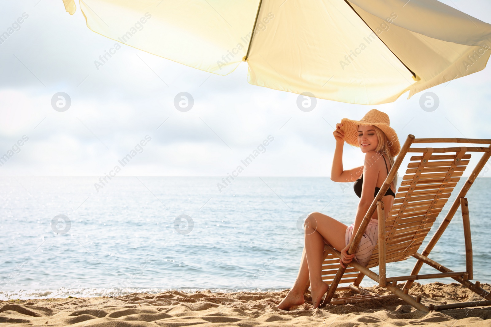 Photo of Woman relaxing on deck chair at sandy beach. Summer vacation