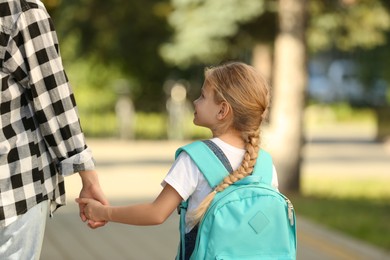 Photo of Little girl with her mother on way to school, back view