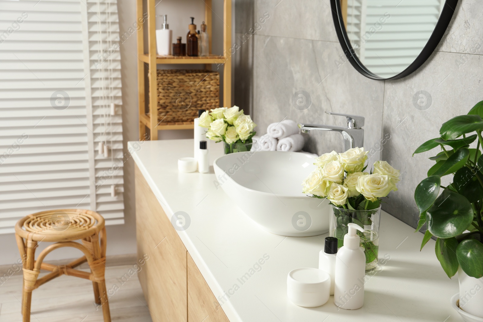 Photo of Beautiful roses and bath accessories near sink in bathroom