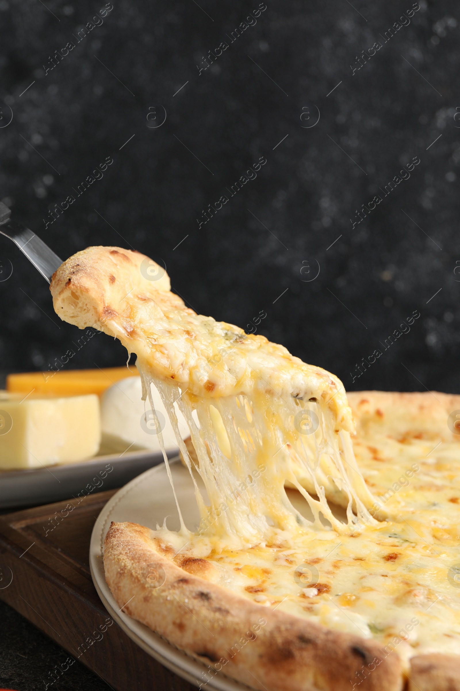 Photo of Taking piece of delicious cheese pizza at table, closeup