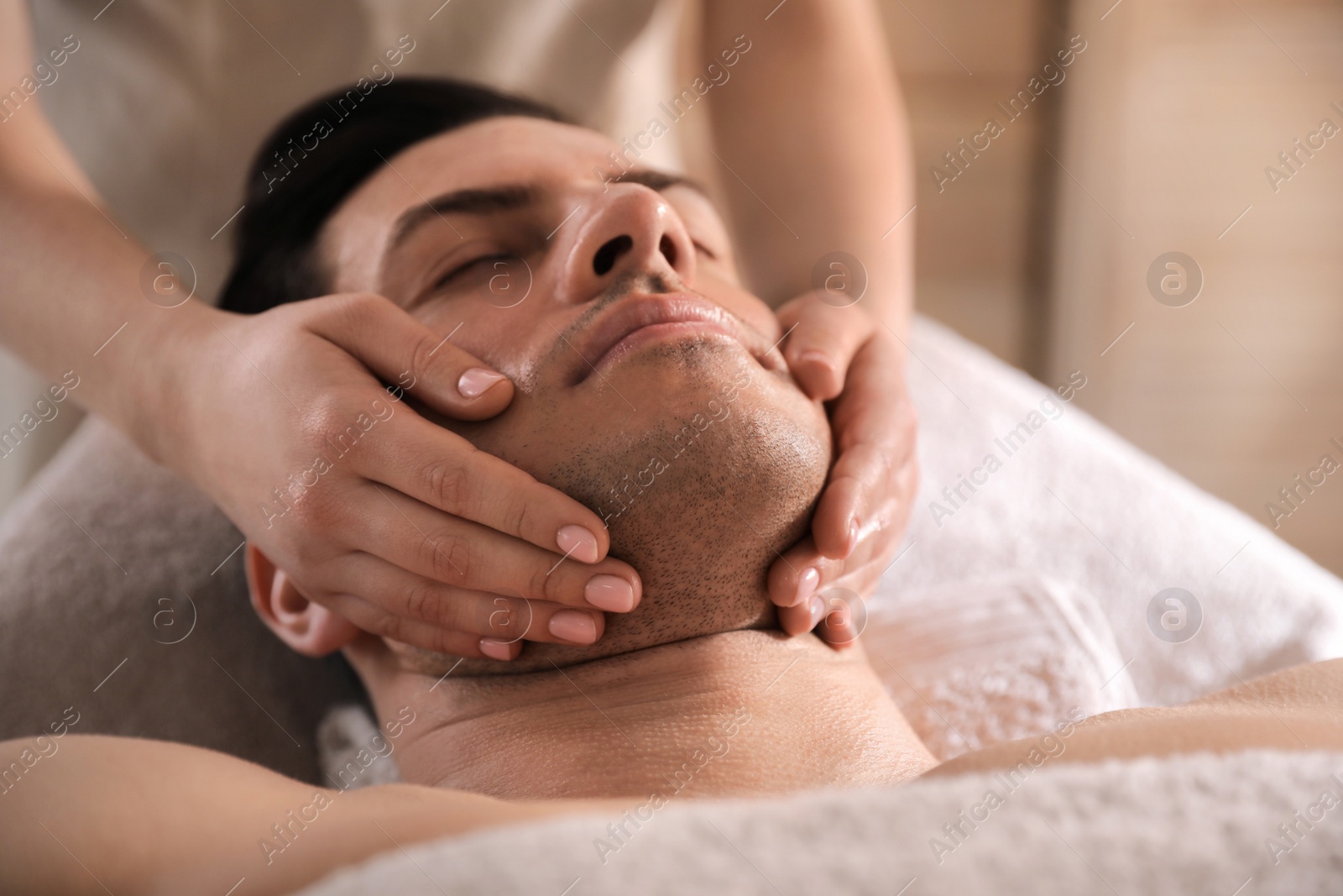 Photo of Man receiving facial massage in beauty salon, closeup