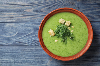 Photo of Tasty kale soup with croutons on blue wooden table, top view. Space for text