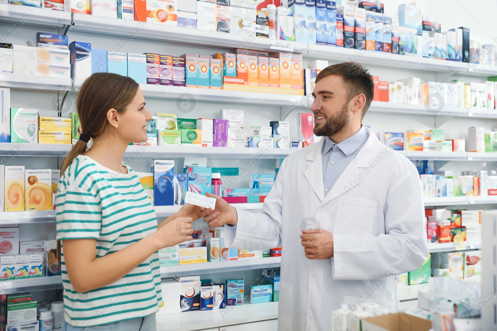 Photo of Professional pharmacist giving pills to customer in modern drugstore