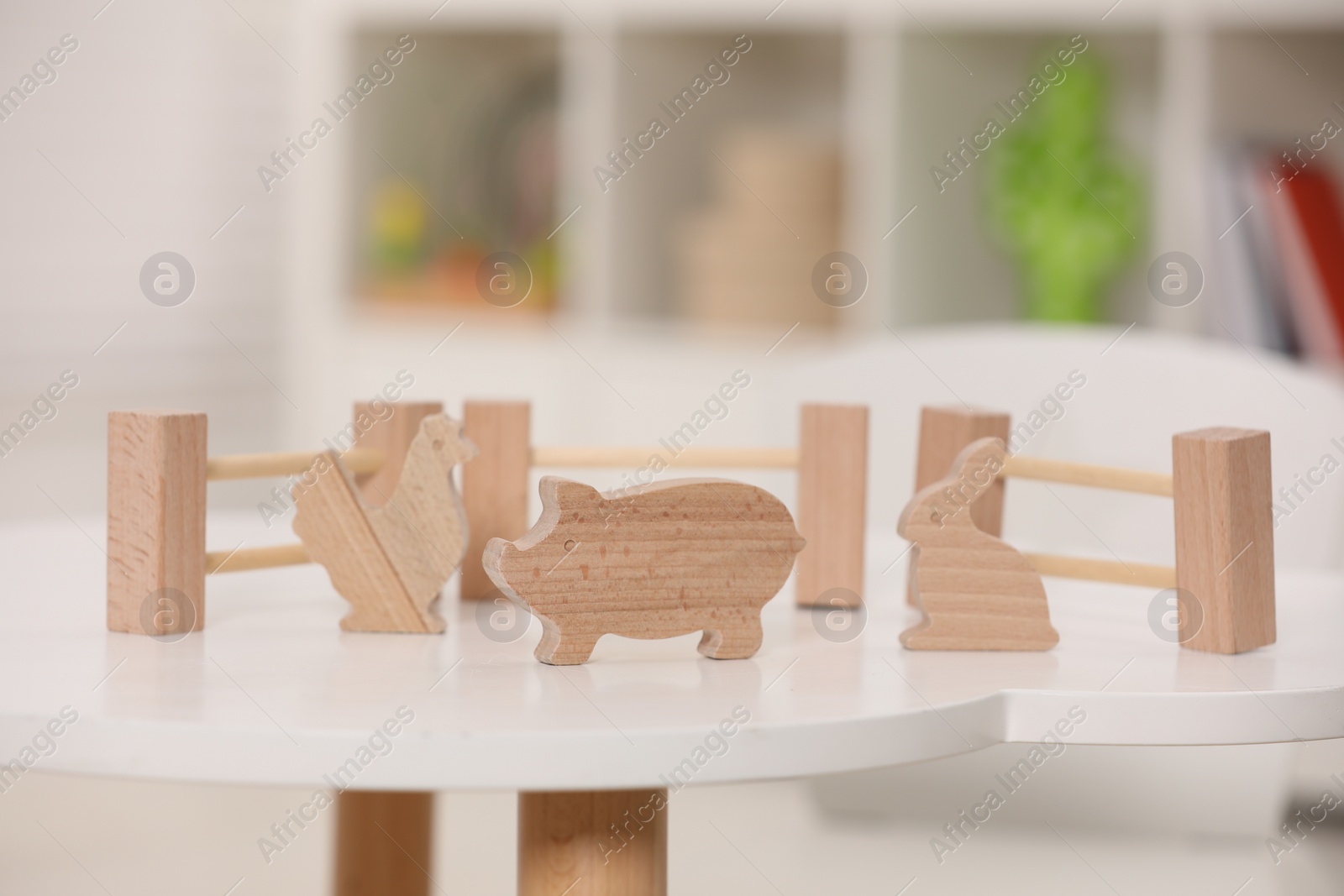 Photo of Set of wooden animals and fence on white table indoors. Educational toy for motor skills development