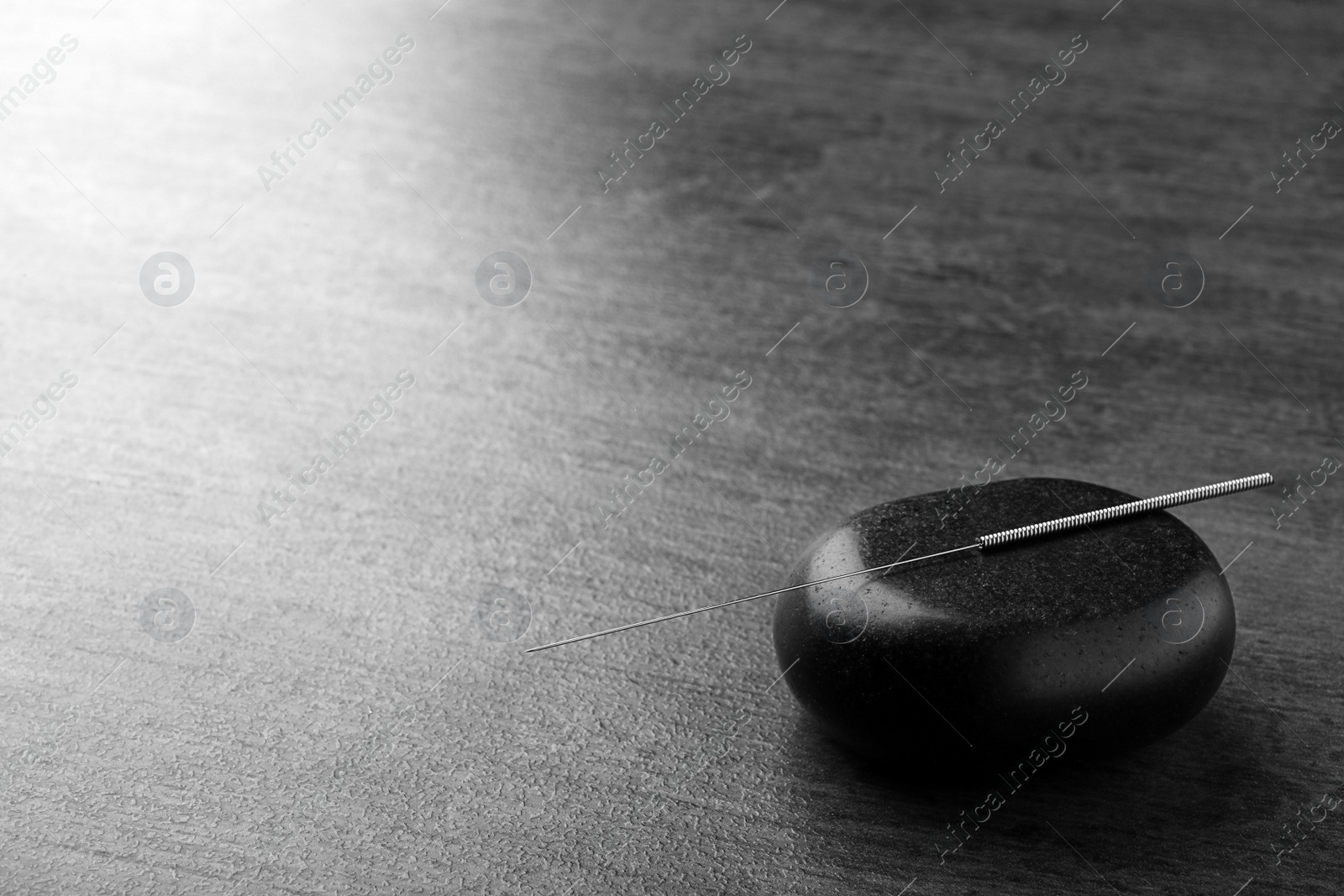 Photo of Acupuncture needle and stone on dark table