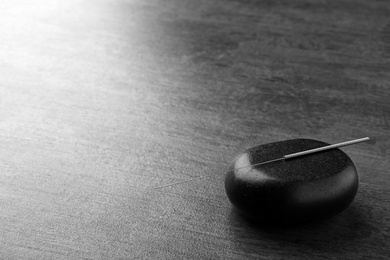 Photo of Acupuncture needle and stone on dark table