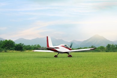 Photo of Ultralight aircraft on green grass near trees