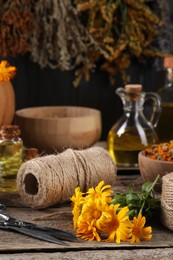 Photo of Calendula flowers, thread and scissors on wooden table. Medicinal herbs