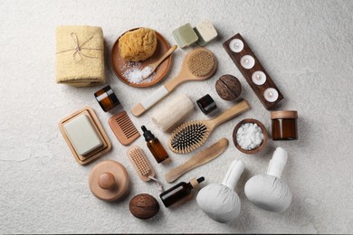 Flat lay composition with different spa products and burning candles on light grey textured table