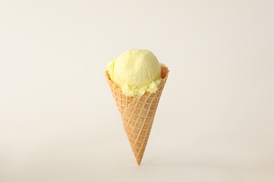 Photo of Delicious yellow ice cream in waffle cone on white background
