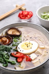 Delicious vegetarian ramen with egg, mushrooms, tofu and vegetables in bowl on table, closeup. Noodle soup