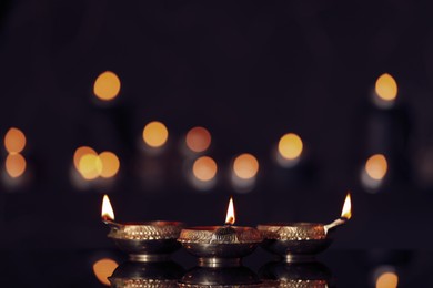 Lit diyas on table against blurred lights. Diwali lamps