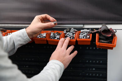 Mechanic with wheel balancing weights at tire service, closeup