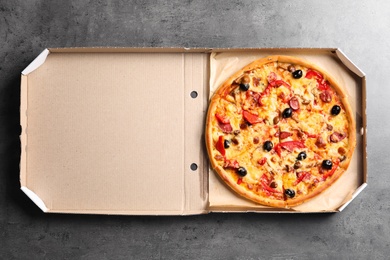 Photo of Cardboard box with delicious pizza on table, top view